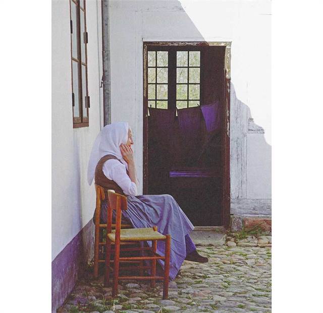 Siddende kvinde i gården - postkort